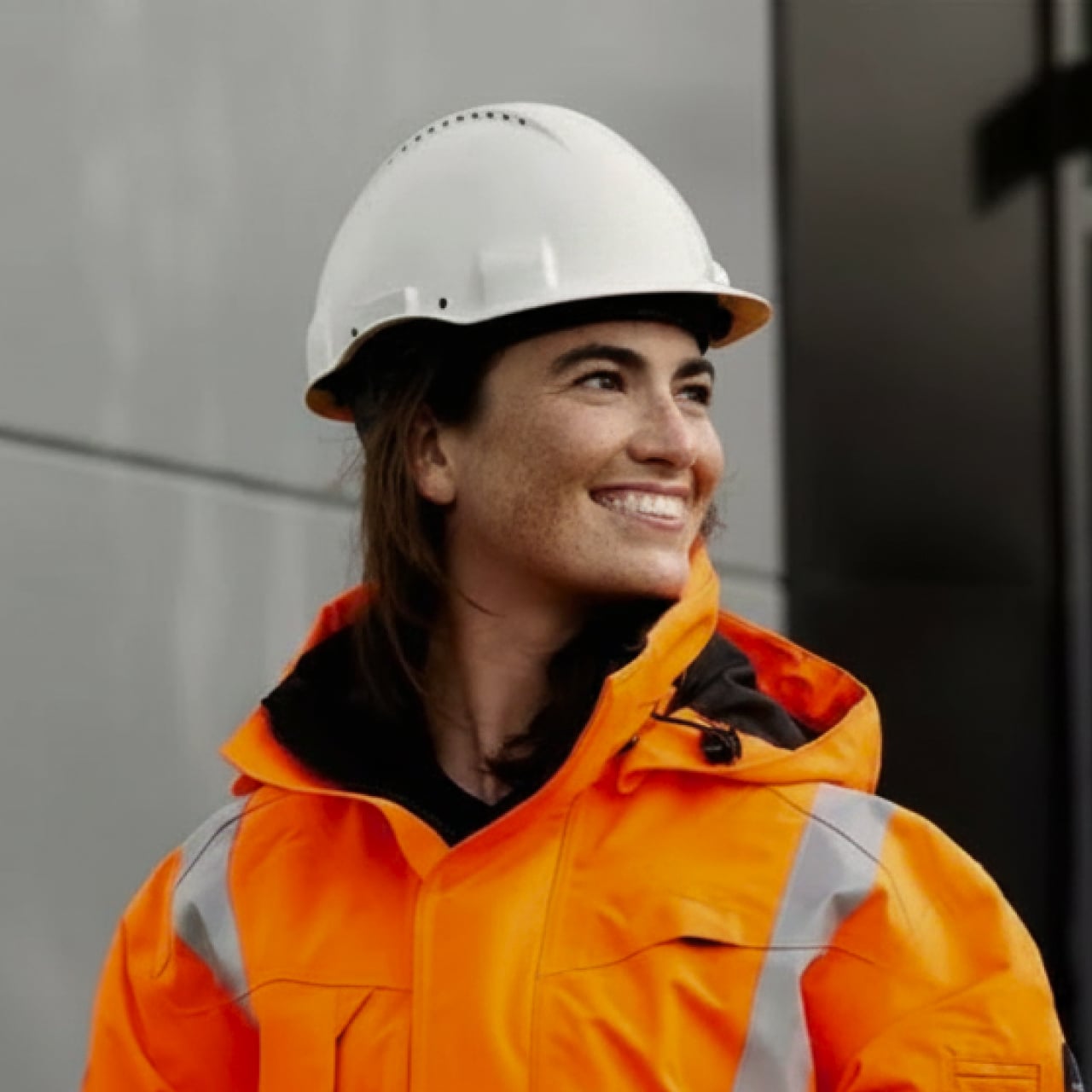 Técnica de capacete e jaqueta laranja sorrindo